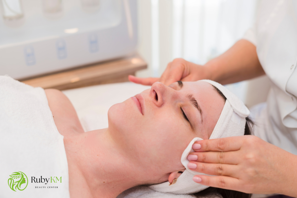 Esthetician providing a facial cleansing treatment to a client